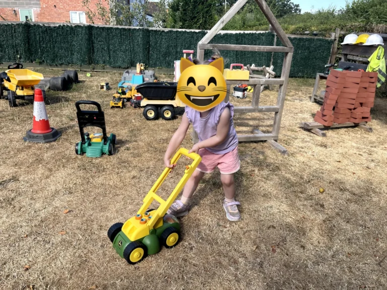 A child pushing a toy lawnmower at Little Hedgehogs Play Garden