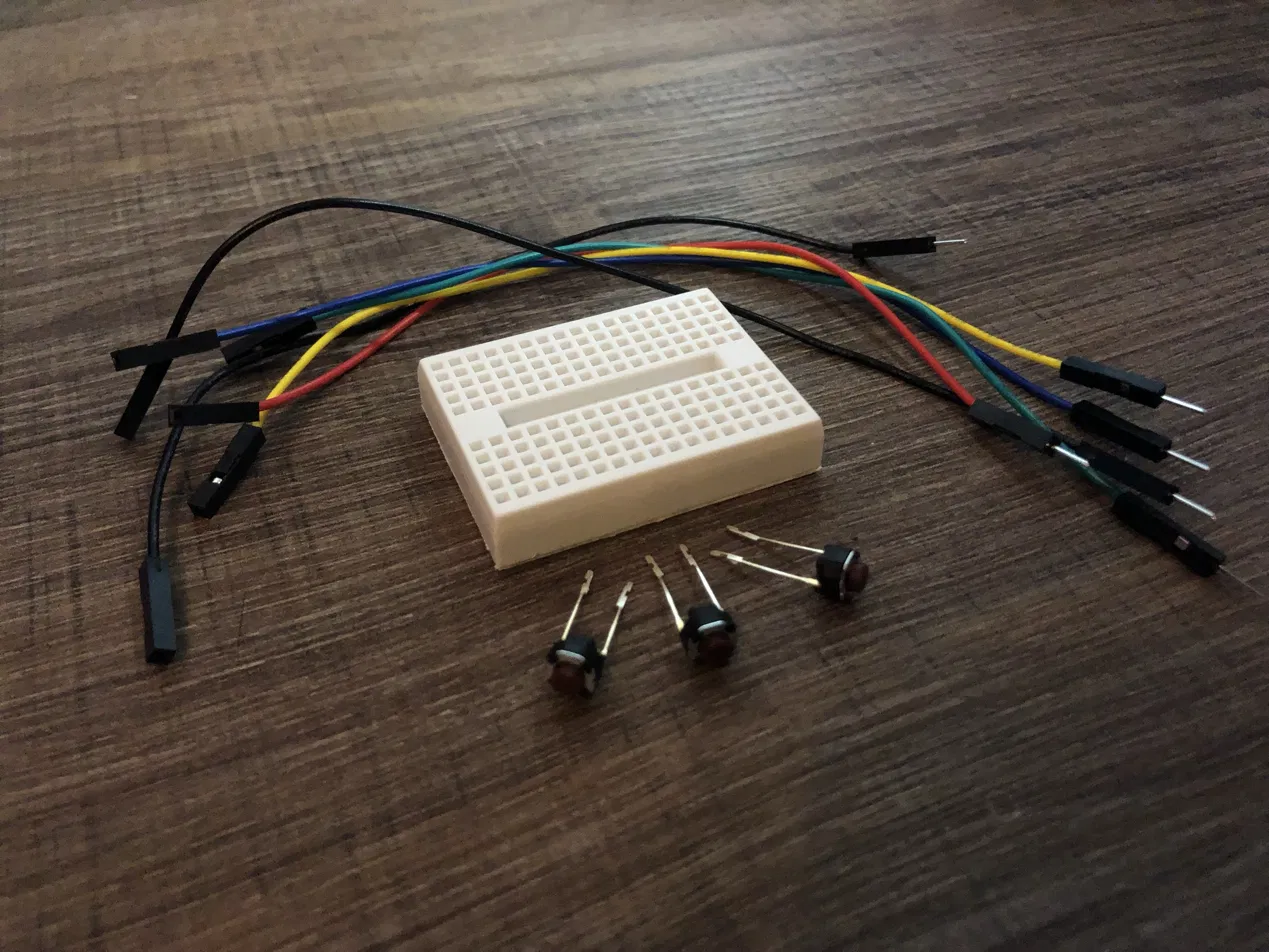 The kit laid out: a mini breadboard, three push buttons and six jumper leads