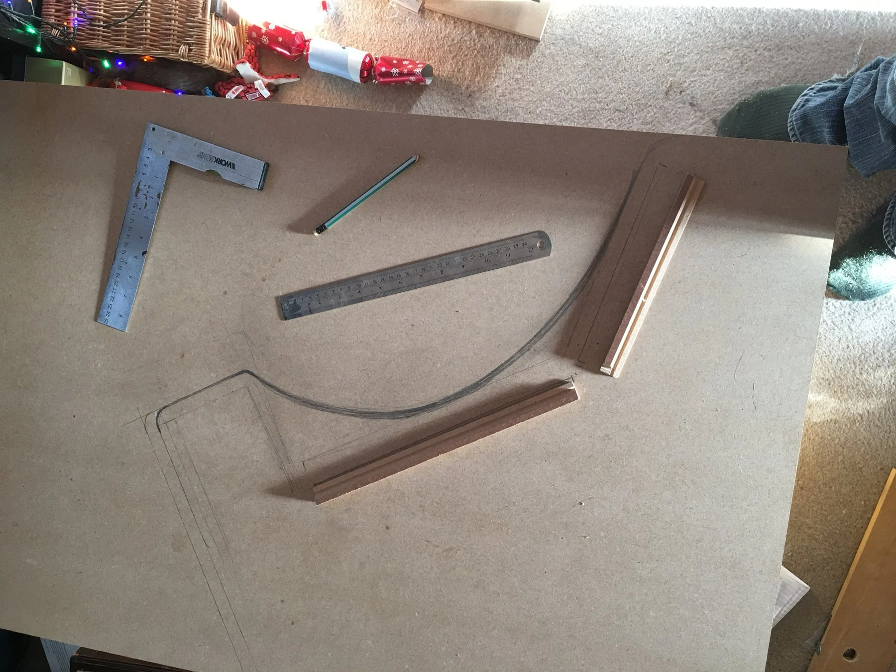 Marking out the side profile on MDF with a square, rule and a bent strip for the curve